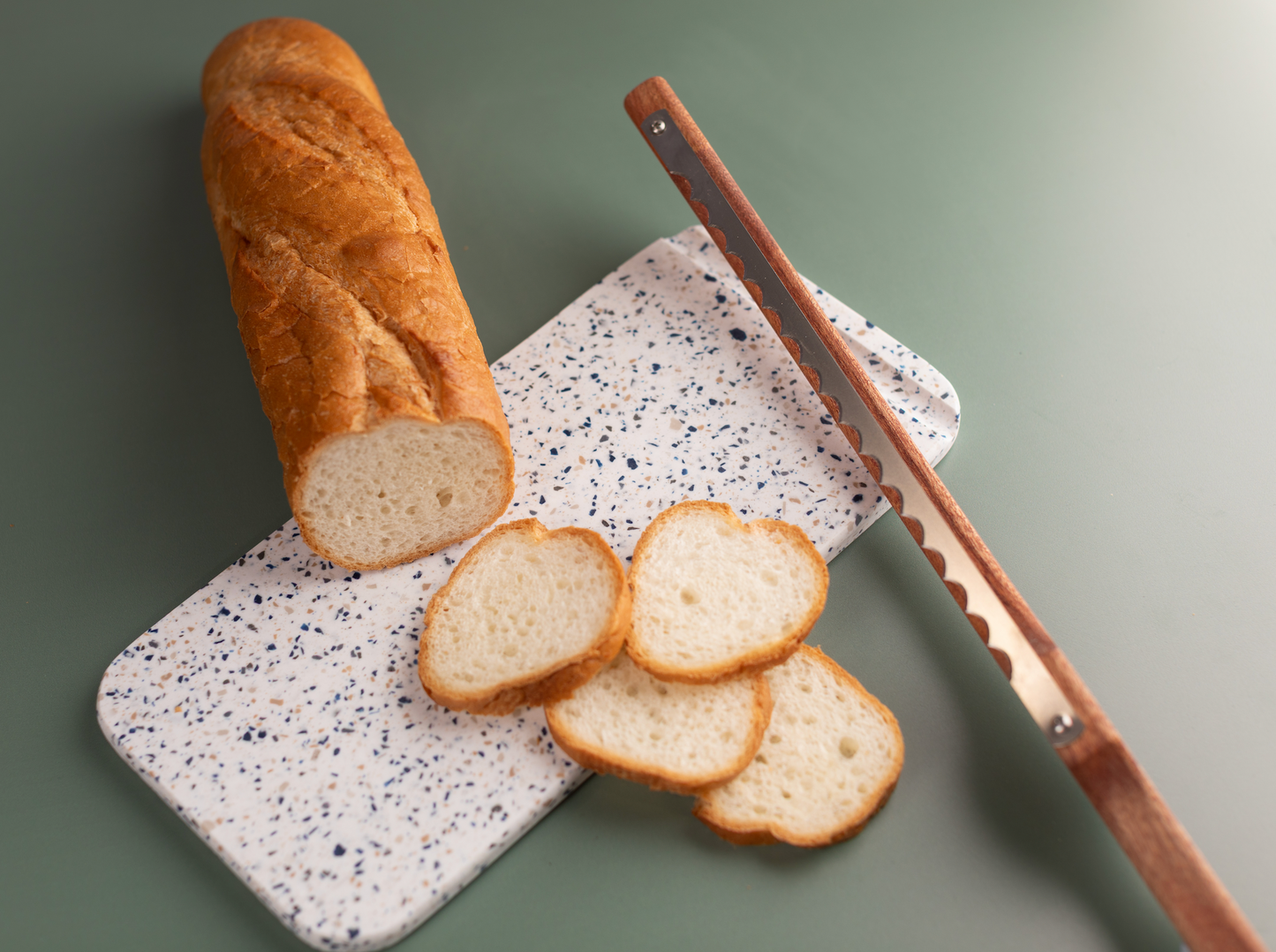 Right-handed Little Bread Winner bread saw displayed alongside a reclaimed Corian bread board