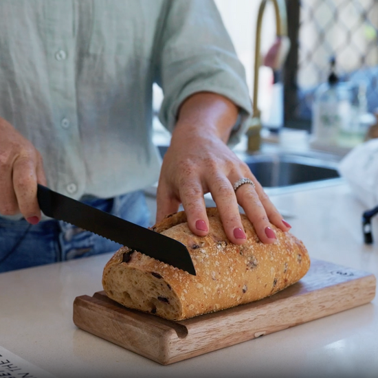 Video comparing a bread knife and a Little Bread Winner bread saw slicing a loaf — the saw cuts cleanly without squashing the bread"