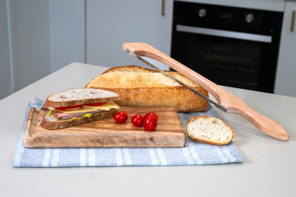 Fresh sandwich and bread loaf on kitchen counter with Little Bread Winner's bread saw and cutting board