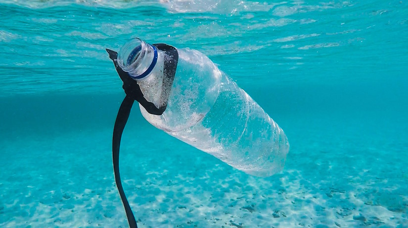 Plastic bottle floating in clear blue ocean water.