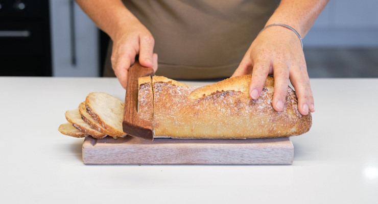 Little Bread Winner founder Cascie, slicing some sourdough bread with our handmade bread saw and using our bread board